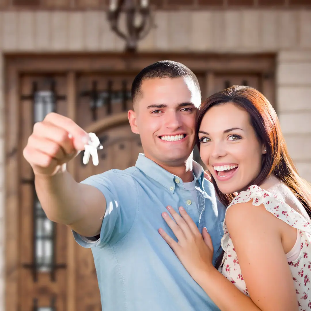 A couple holding a pair of keys to their house