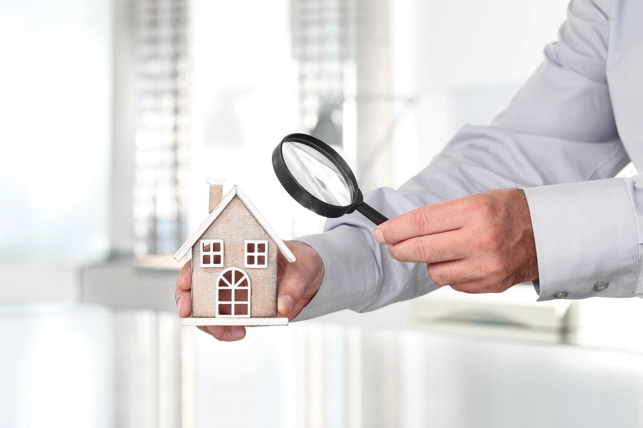 A person holding a magnifying glass over a model home