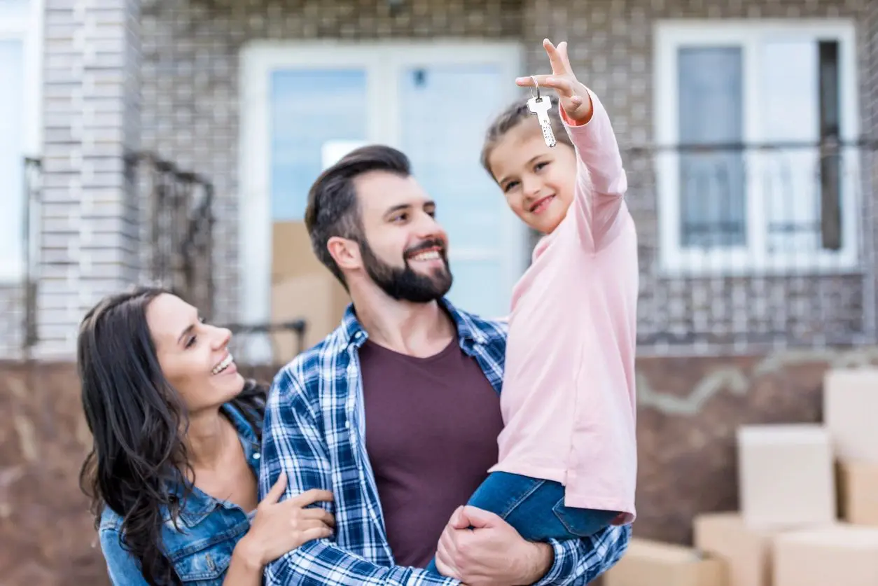 A couple looking at their kid holding house keys