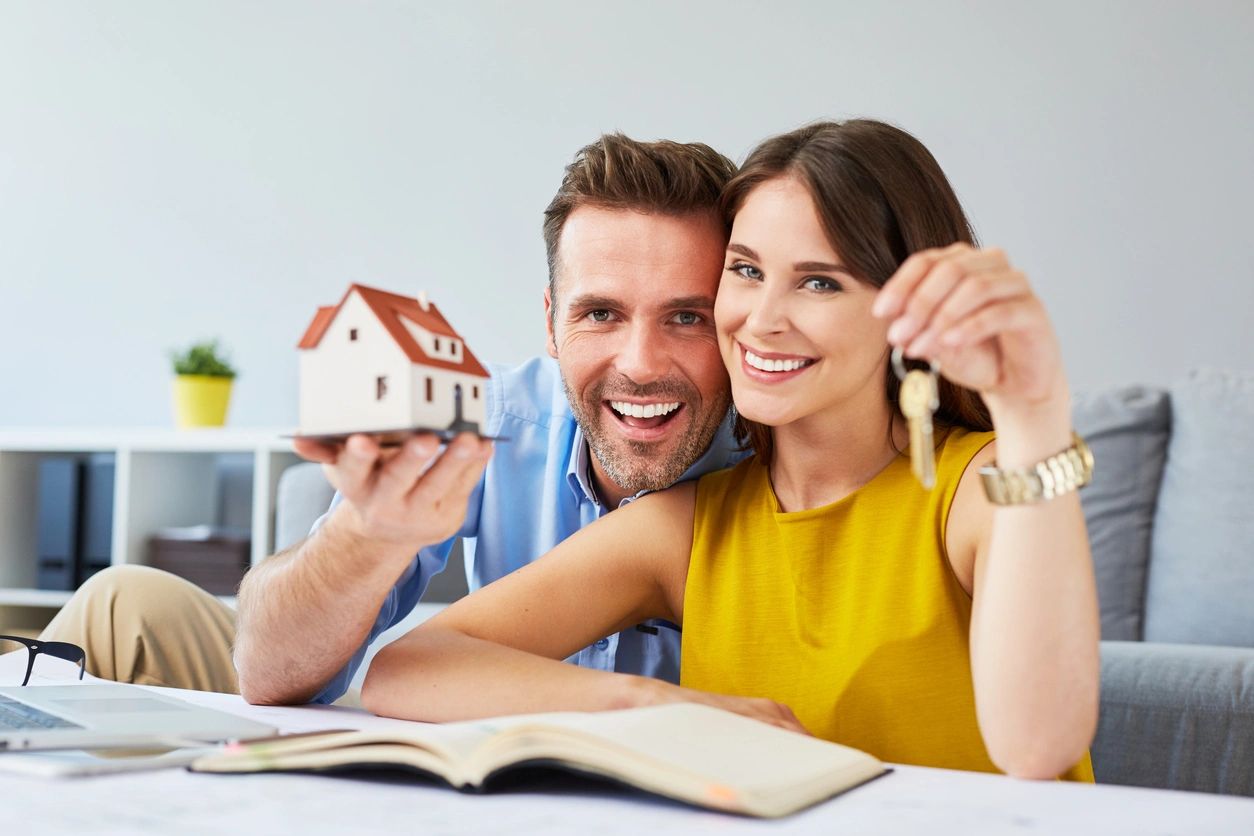 A couple holding a model home and house keys