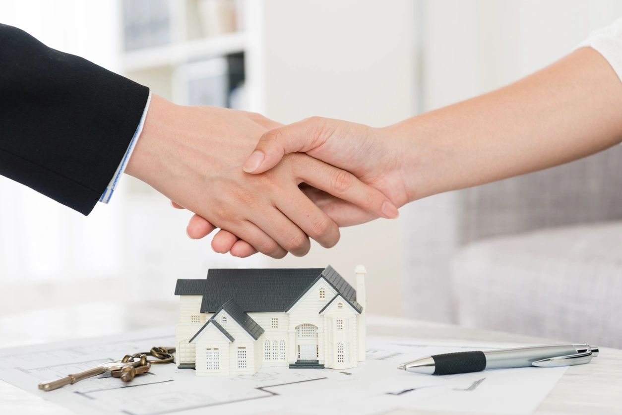 Two people shaking hands over a white model home